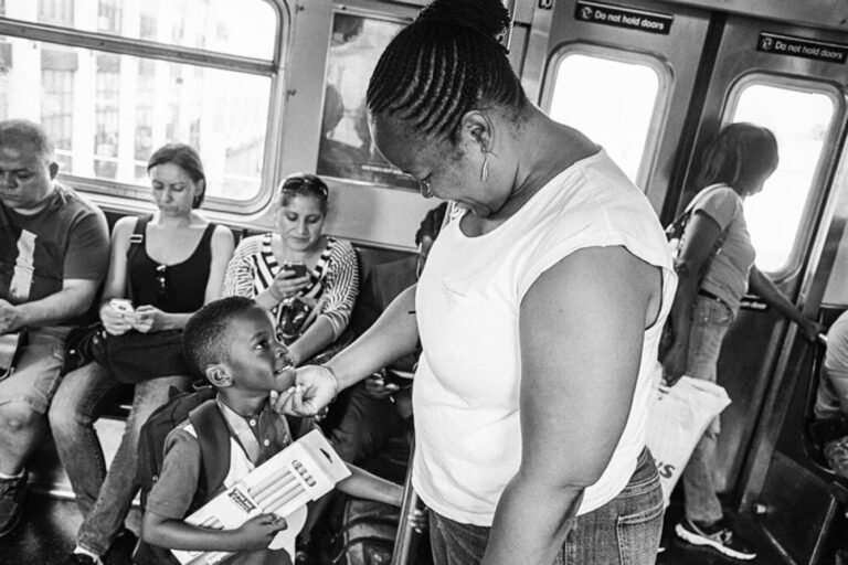 Black and white photograph taken on a subway train where a mother and child look at each other with love.